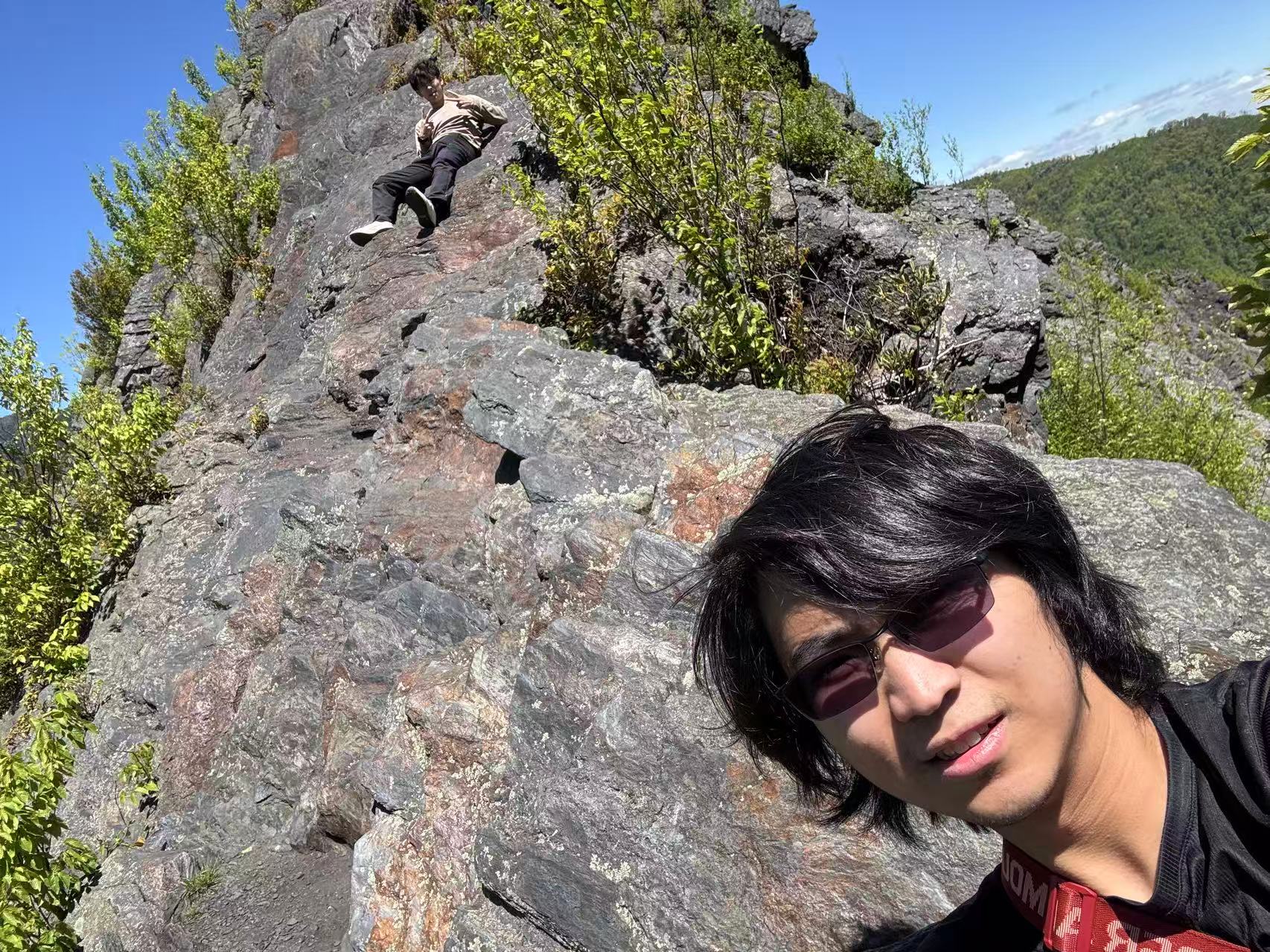 A hiking selfie among rocks and greenery on a sunny day